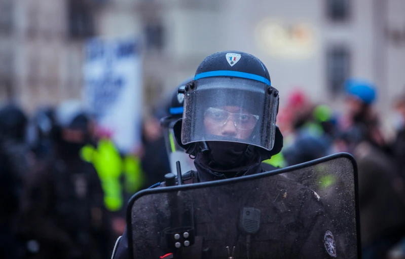 a protester wearing a black suit and holding a skateboard