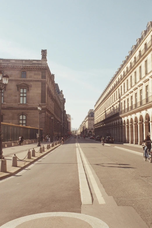 people riding bicycles on a road next to large buildings