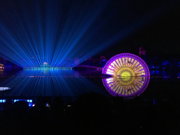 a ferris wheel with a massive light show in the background