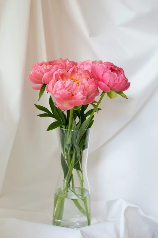 a vase filled with pink flowers on top of a white cloth