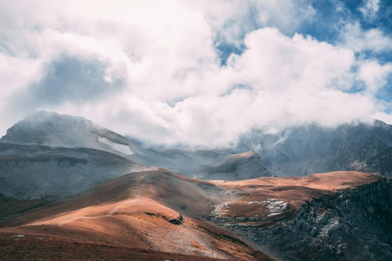 view of mountains and clouds with grass in the foreground