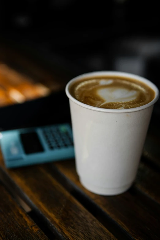 a coffee with a cell phone in it is sitting on the table