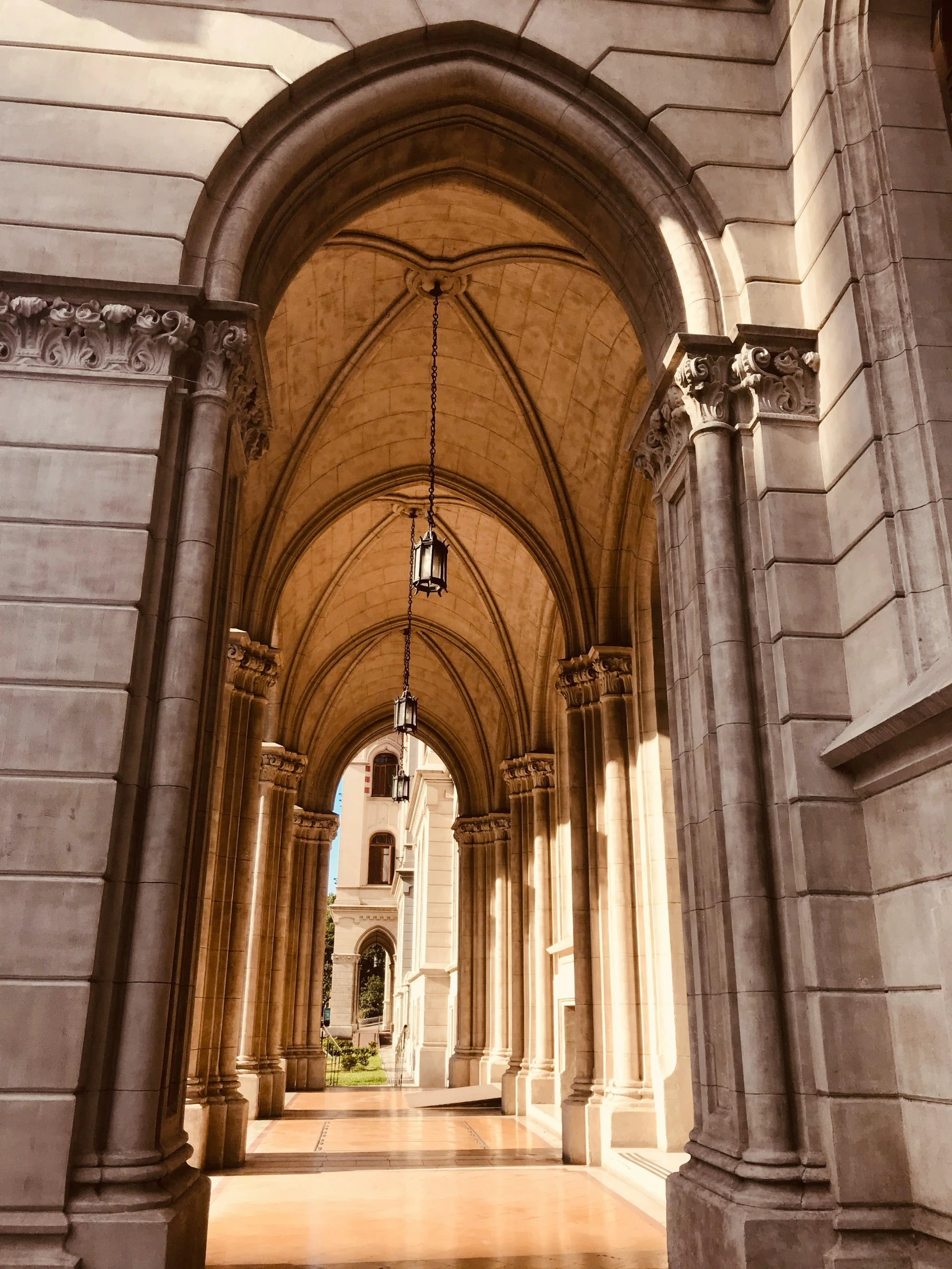 a walkway with columns and stone architecture leading to a clock tower