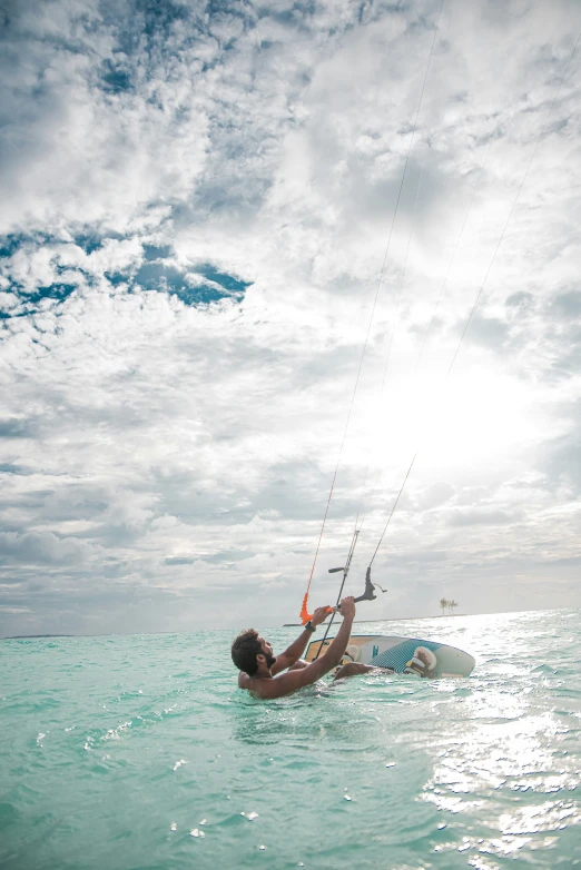 person on surfboard kite surfing through the water