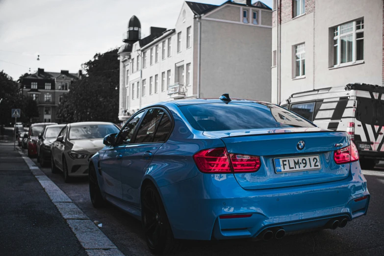 a blue bmw parked in front of some parked cars