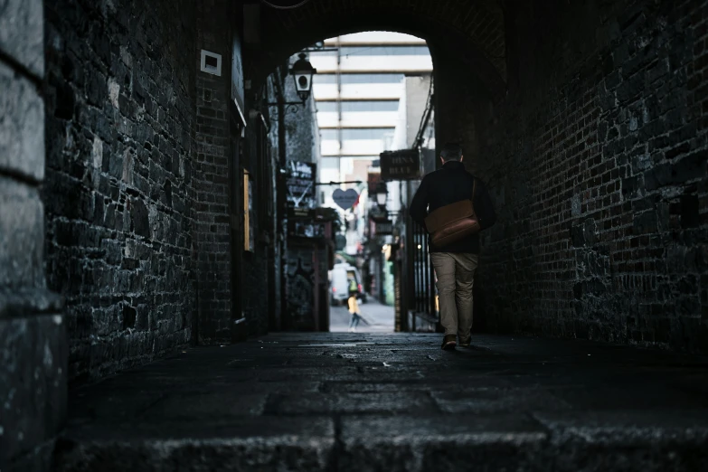 a person walking down an alley way with bags in hand