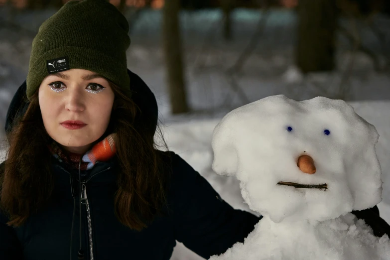 a young woman holding a snowman with his hand on the snow