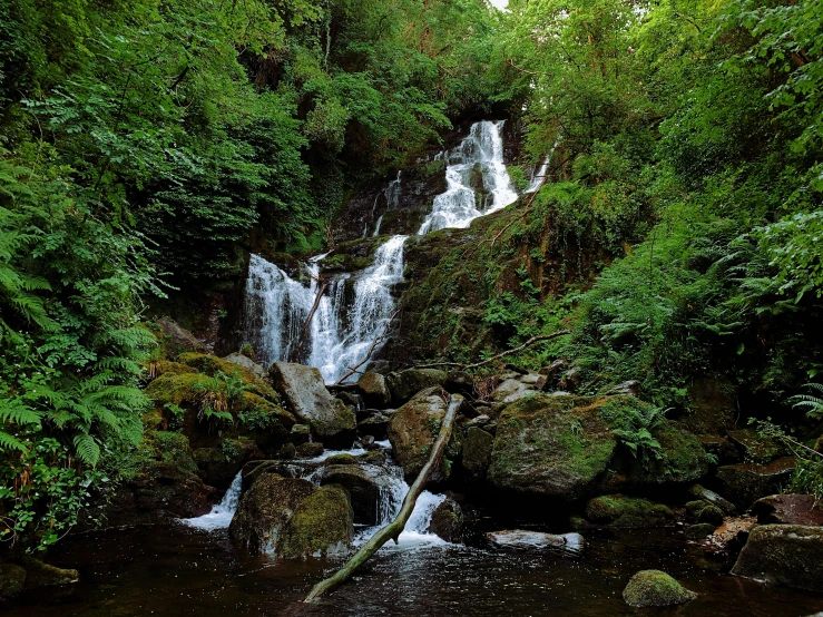 there is a waterfall in the woods where many people are hiking