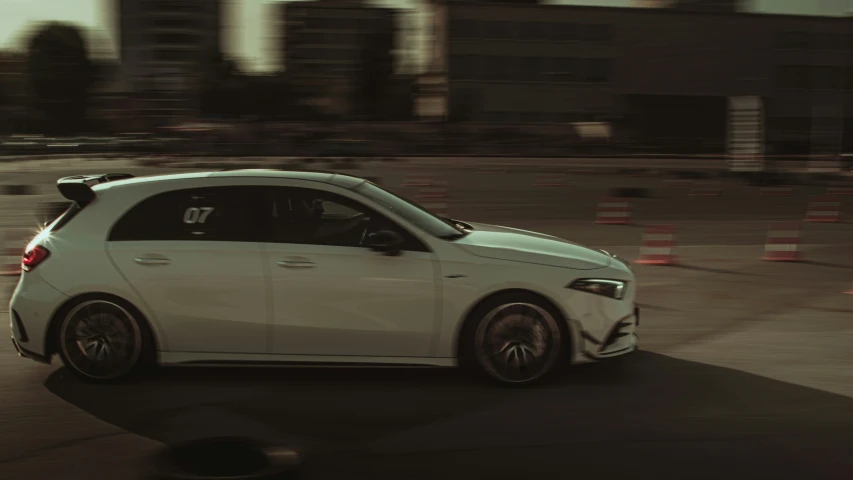 the front end of a white car on a city street