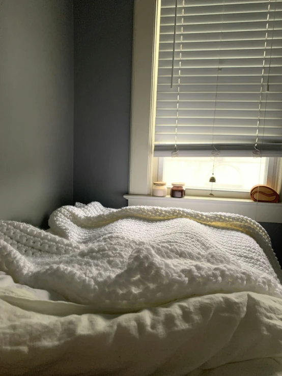 an unmade bed with white blankets and pillows