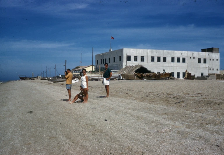 a group of three people standing on top of a beach