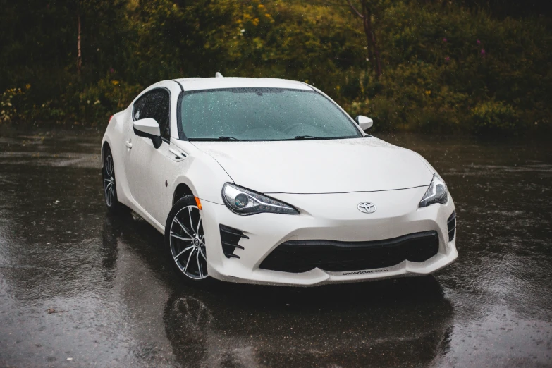 white toyota sports car in the rain, parked on a pavement