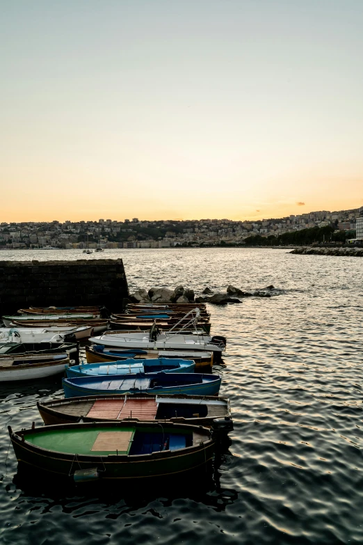 small boats tied to the dock while the sun is setting