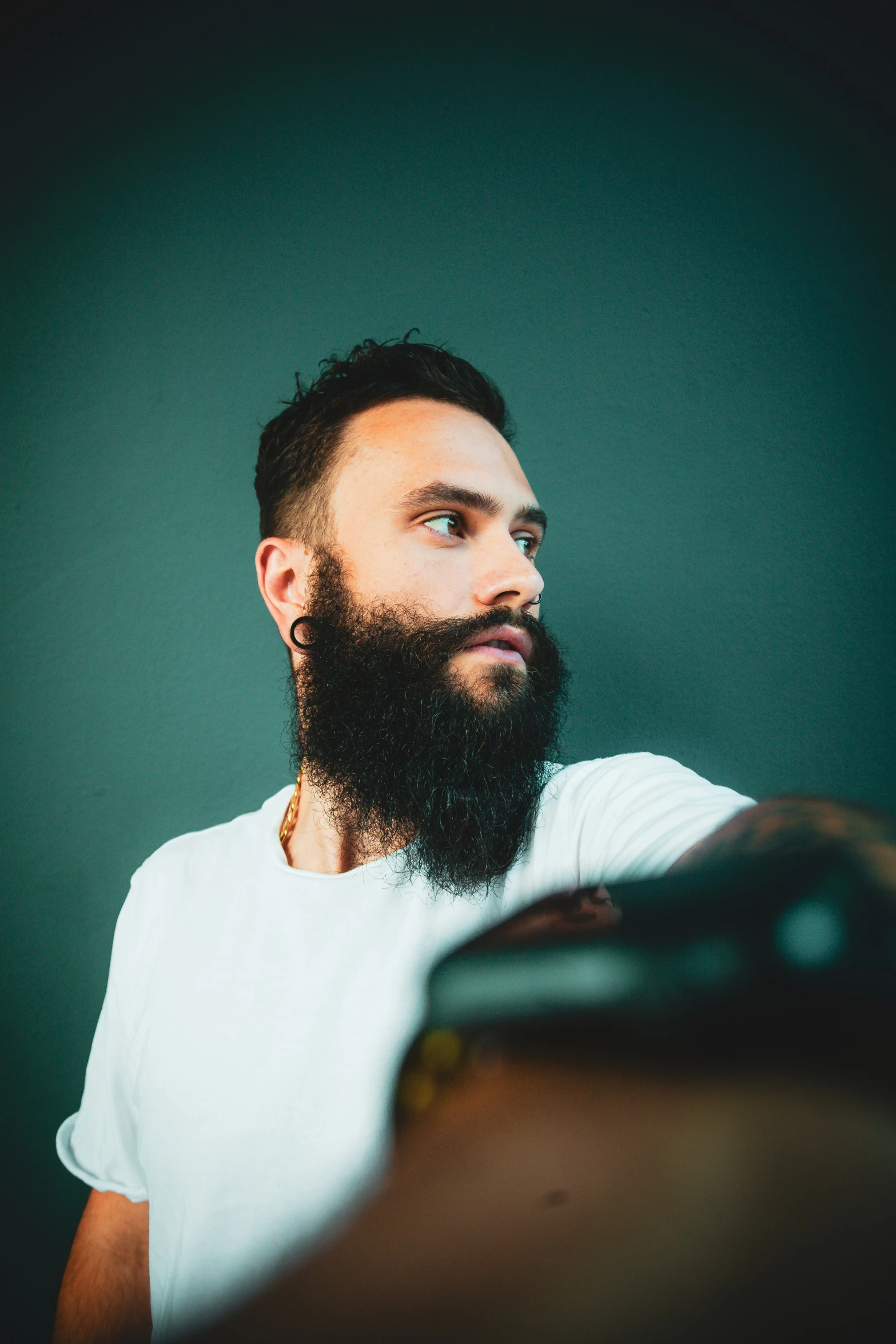 a bearded man in a white shirt staring to the side