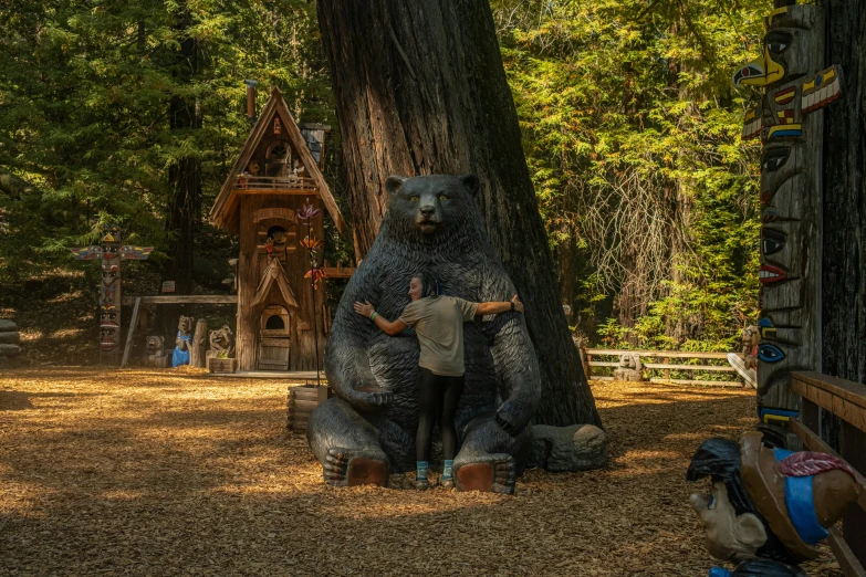 a man leaning on the head of a large fake bear statue