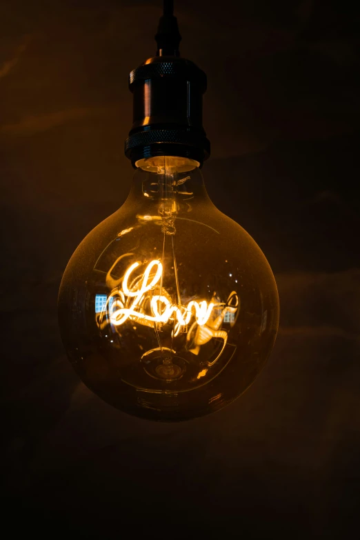 a large light bulb has the word love written in cursive lettering