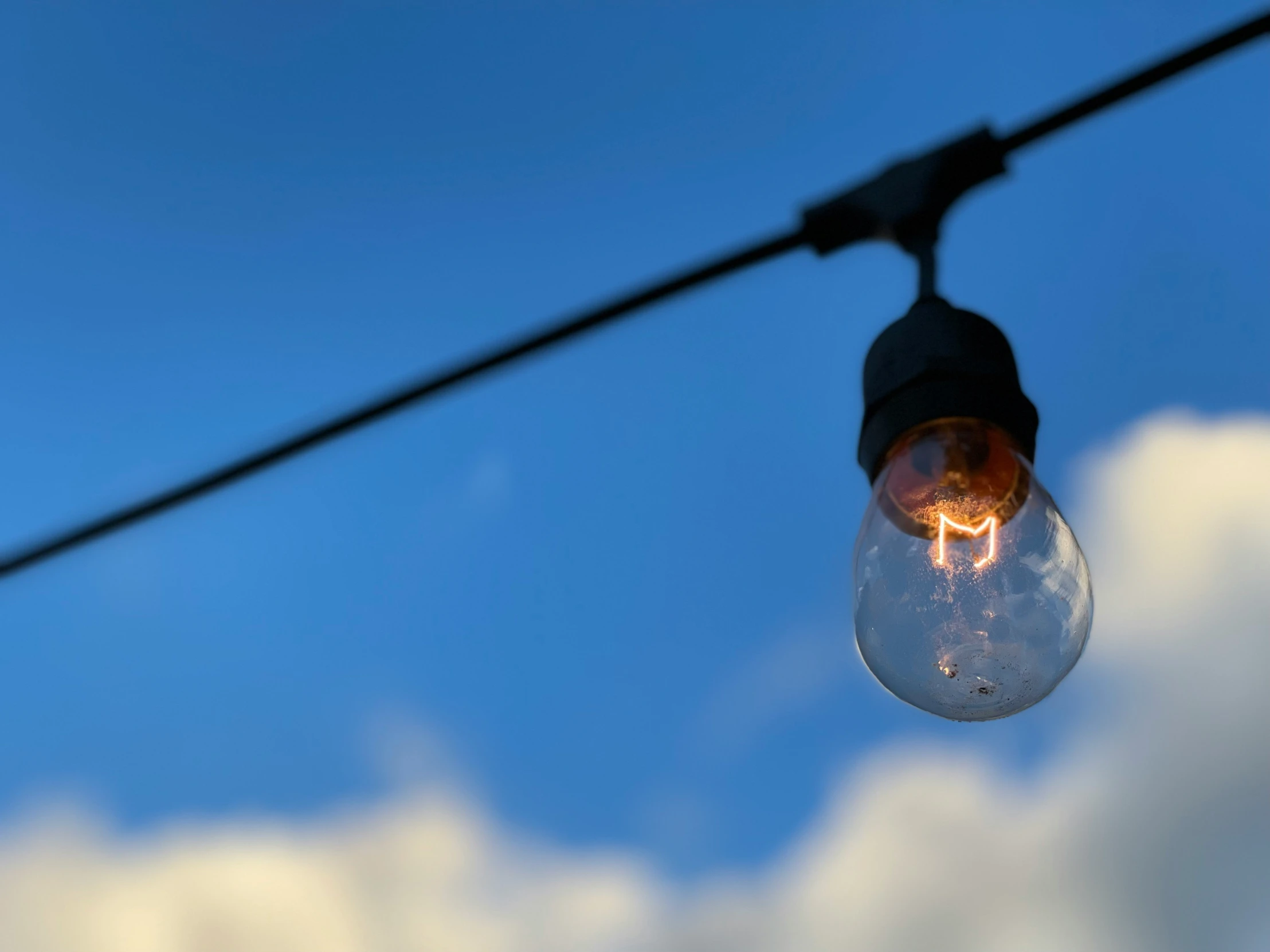 an outdoor street light sitting under a blue cloudy sky