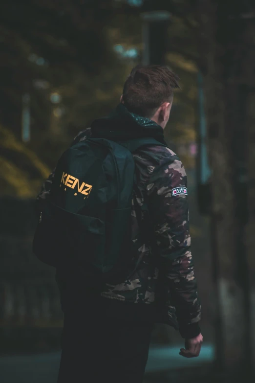 a man walking with his back turned and carrying his black and yellow backpack