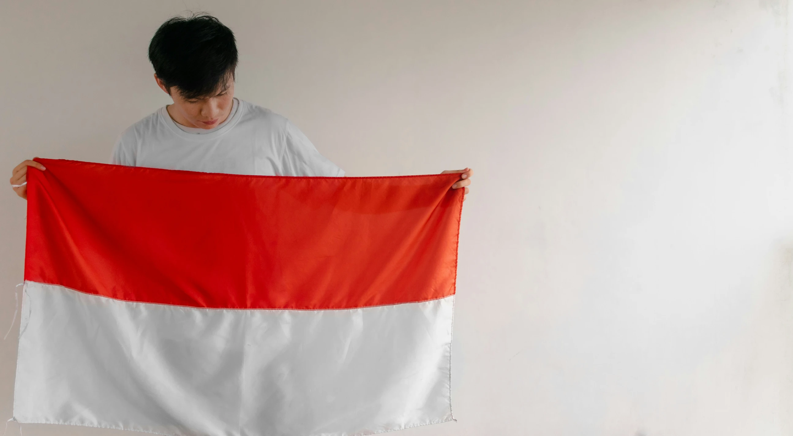 a man holding up a flag in a white room