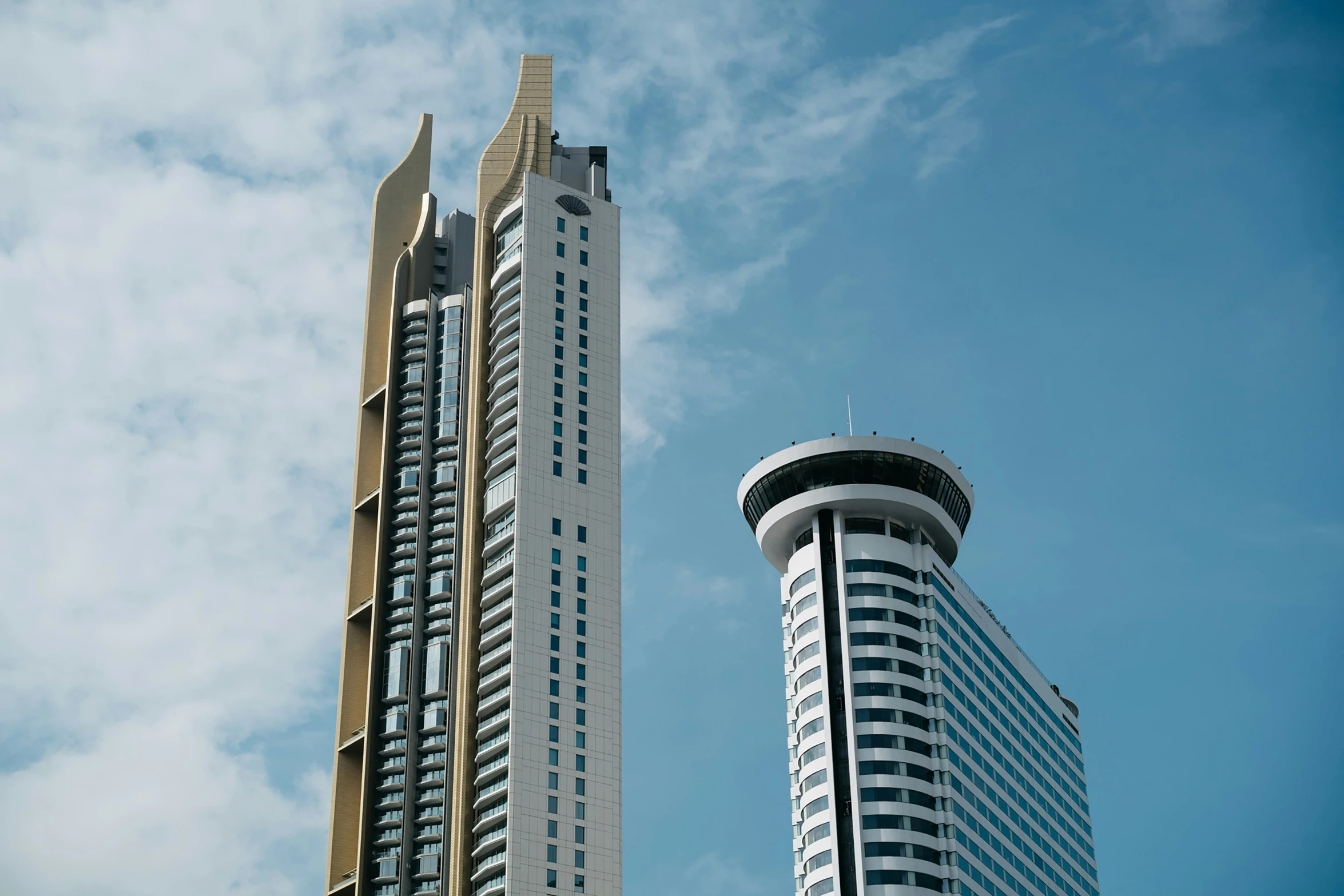 two skyscrs rise above each other against the blue sky