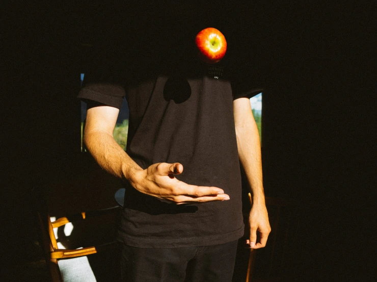 a person in black standing with an apple on their head