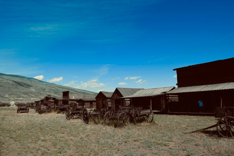 an old house sits outside near mountains and a hayfield