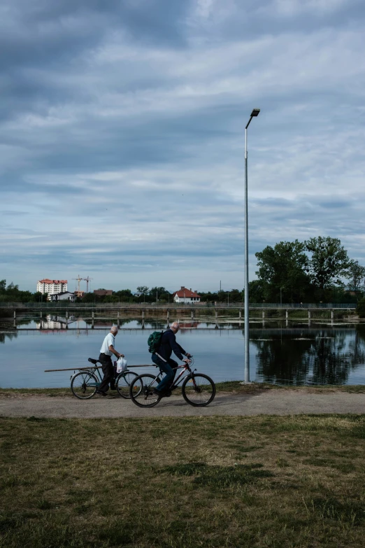 two people are riding bikes by the water