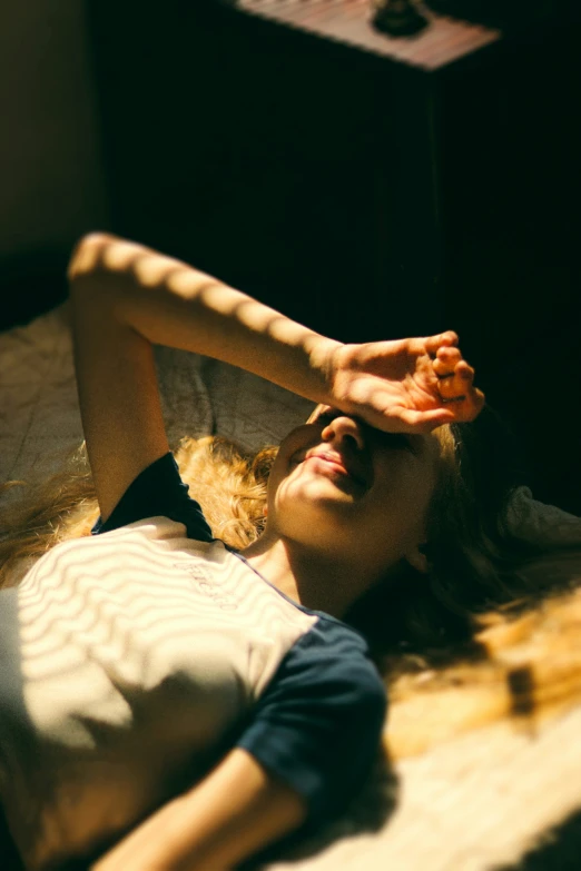 a person laying down on a bed with their hand on her head