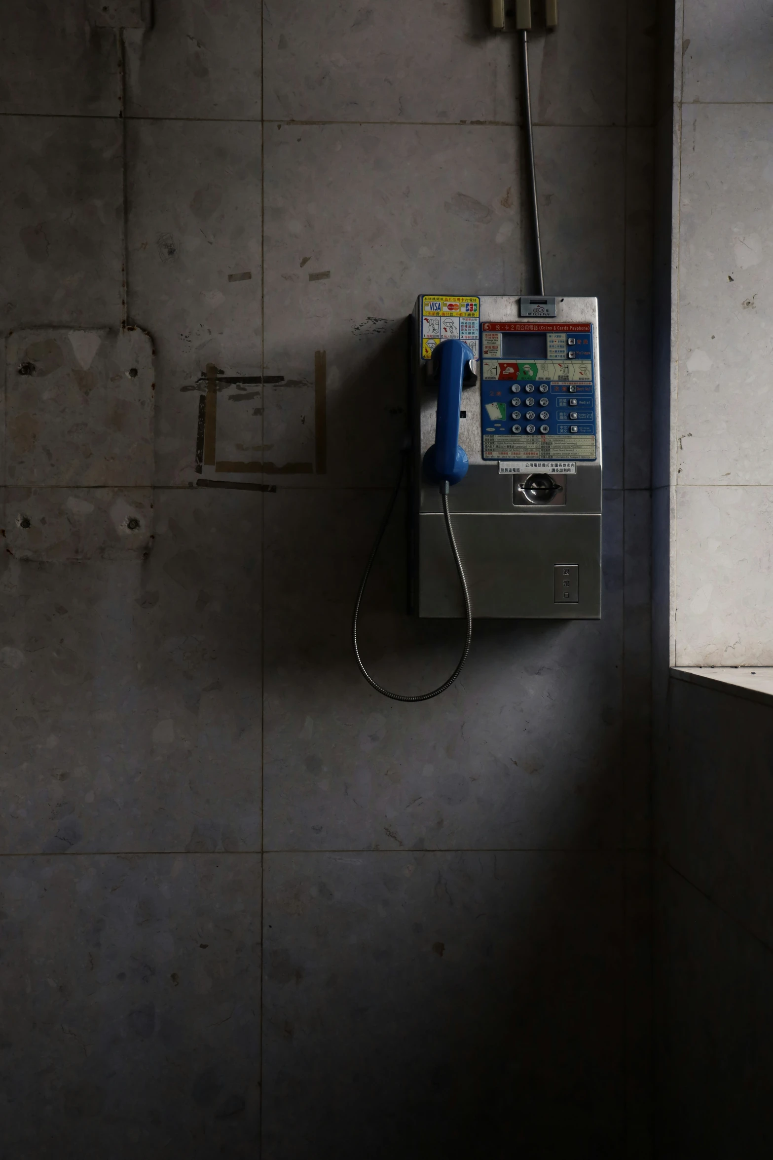 an old phone hangs on a cement wall