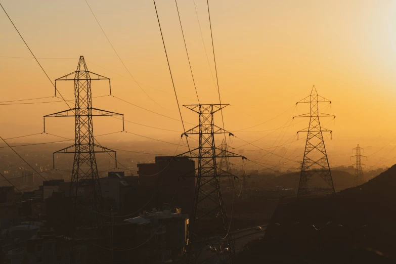 the sun rises as power poles stand in the distance