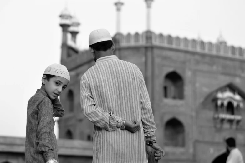 this is a man and boy looking towards soing while standing in front of a building