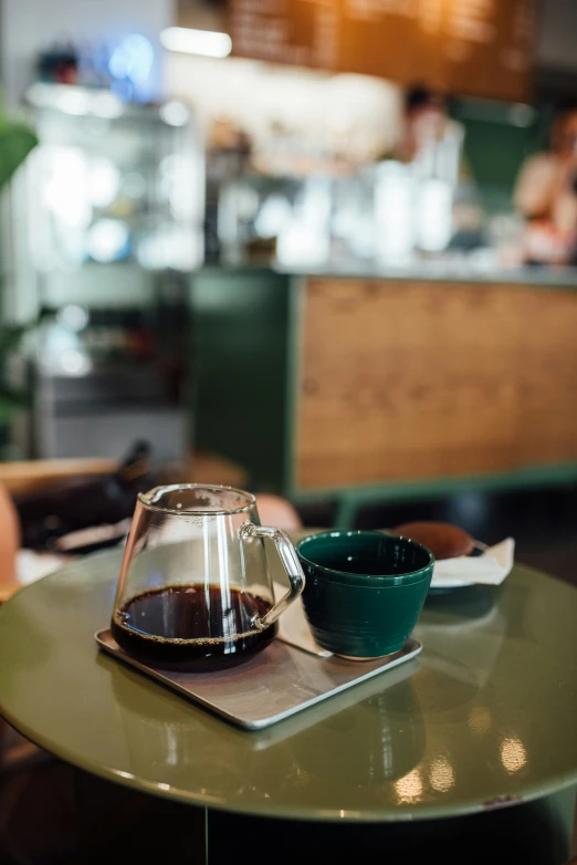 a table with a tea kettle on it, and a cup of coffee sits next to it