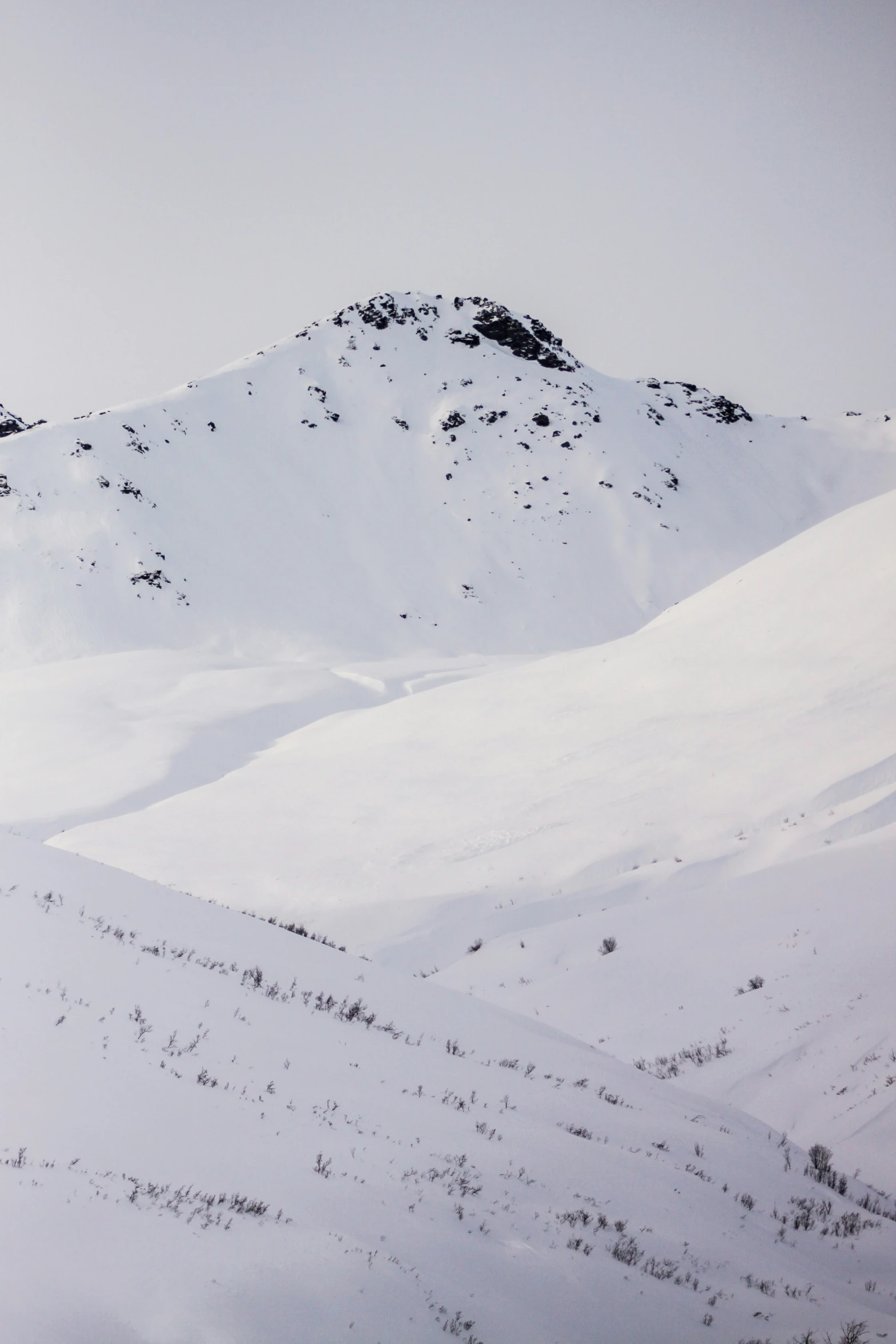 the mountain side has very large white snow covered slopes