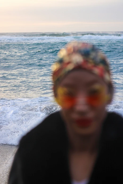 a woman with bright sunglasses and a bandana is at the beach