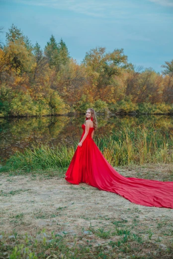 the woman in the red dress is standing by the water
