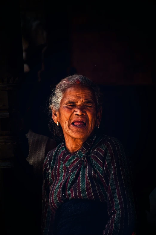 an elderly woman laughs with a dark background