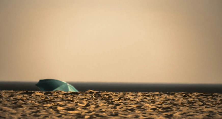 a blue umbrella is on the beach in the sand