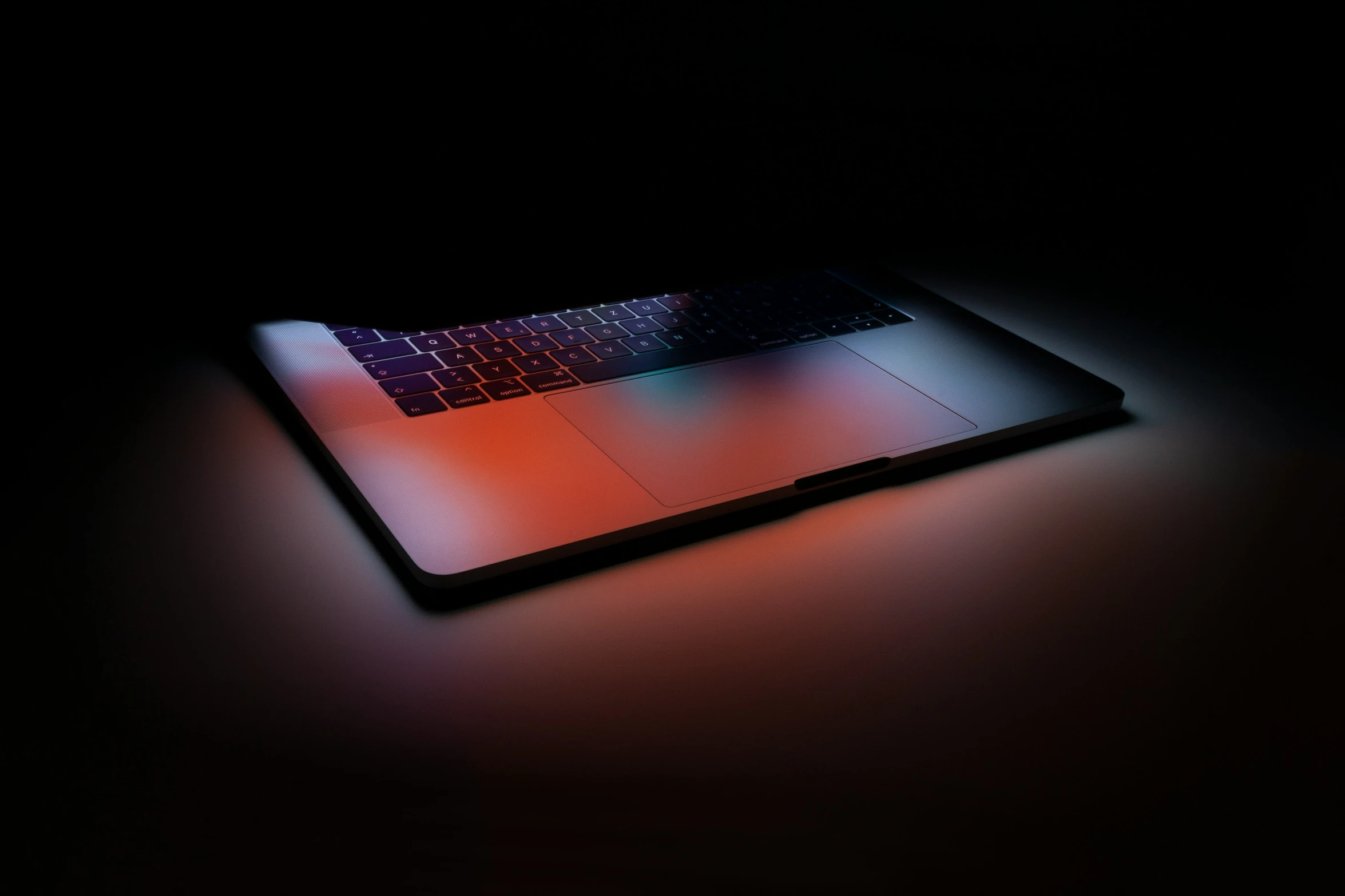 an illuminated laptop with a black background