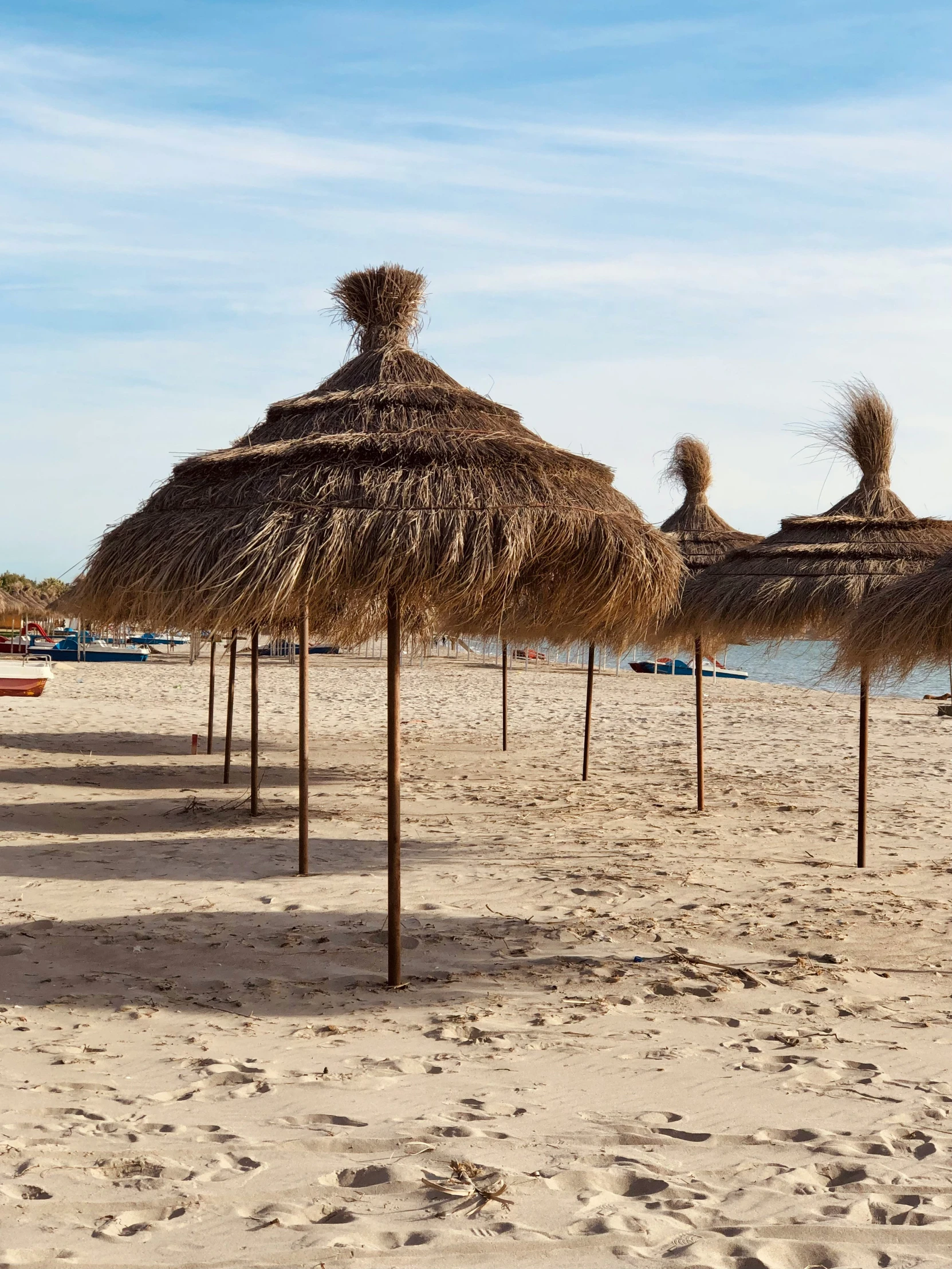 straw umbrellas are sitting on the beach next to the water