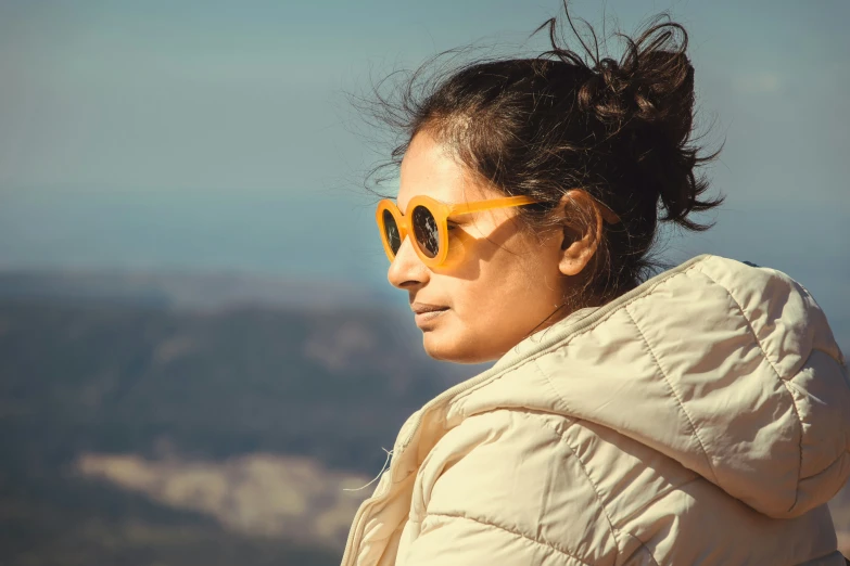 a woman wearing sunglasses on top of a mountain