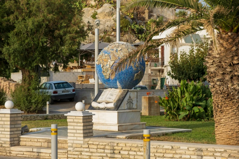 an artistic statue in front of palm trees and parked cars