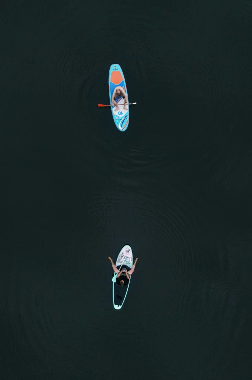 two people on boards are swimming in the water