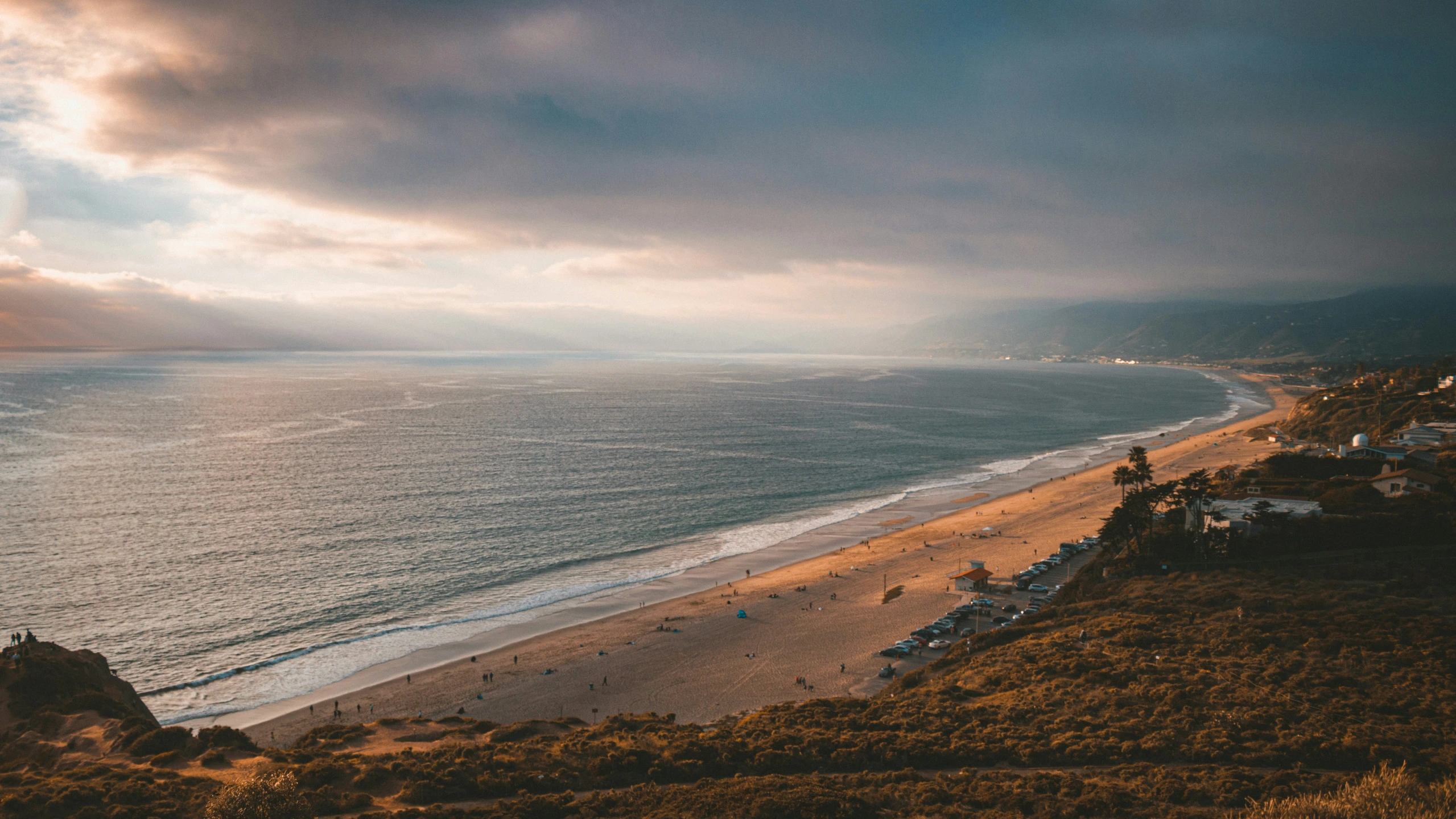 a sandy beach at sunset and an overcast sky