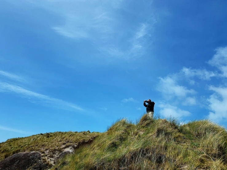 people stand on a hill top, surrounded by grass