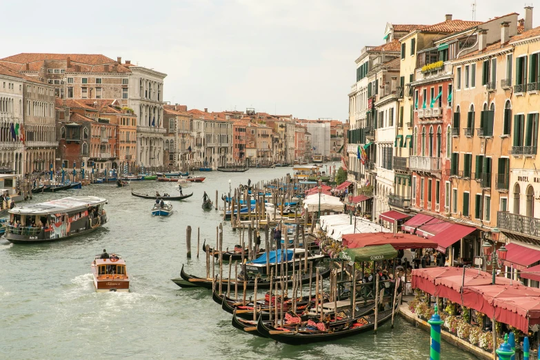 many boats in the middle of a canal filled with buildings