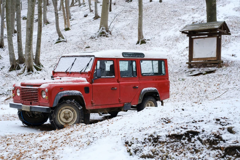 the red jeep is parked on the snowy hillside