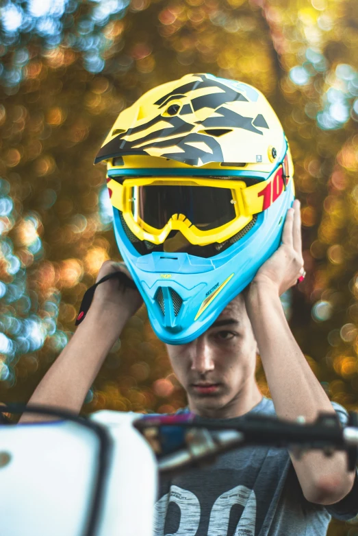 a young man holding up his helmet to his face