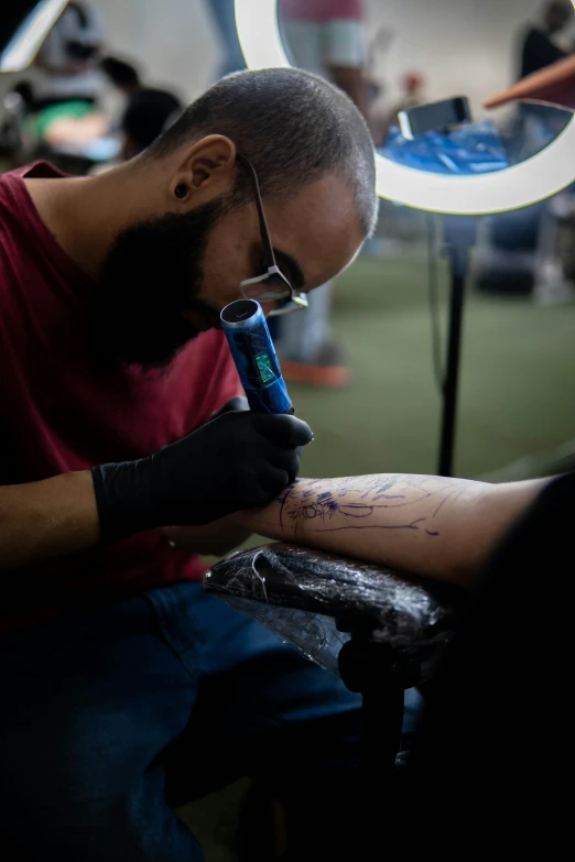 a man is sitting down and writing soing on his arm