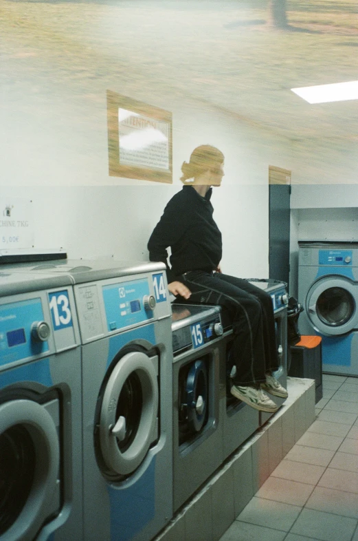 the man in black is sitting on top of the washer