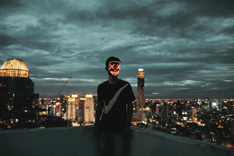 a man wearing a skull mask while standing on top of a building